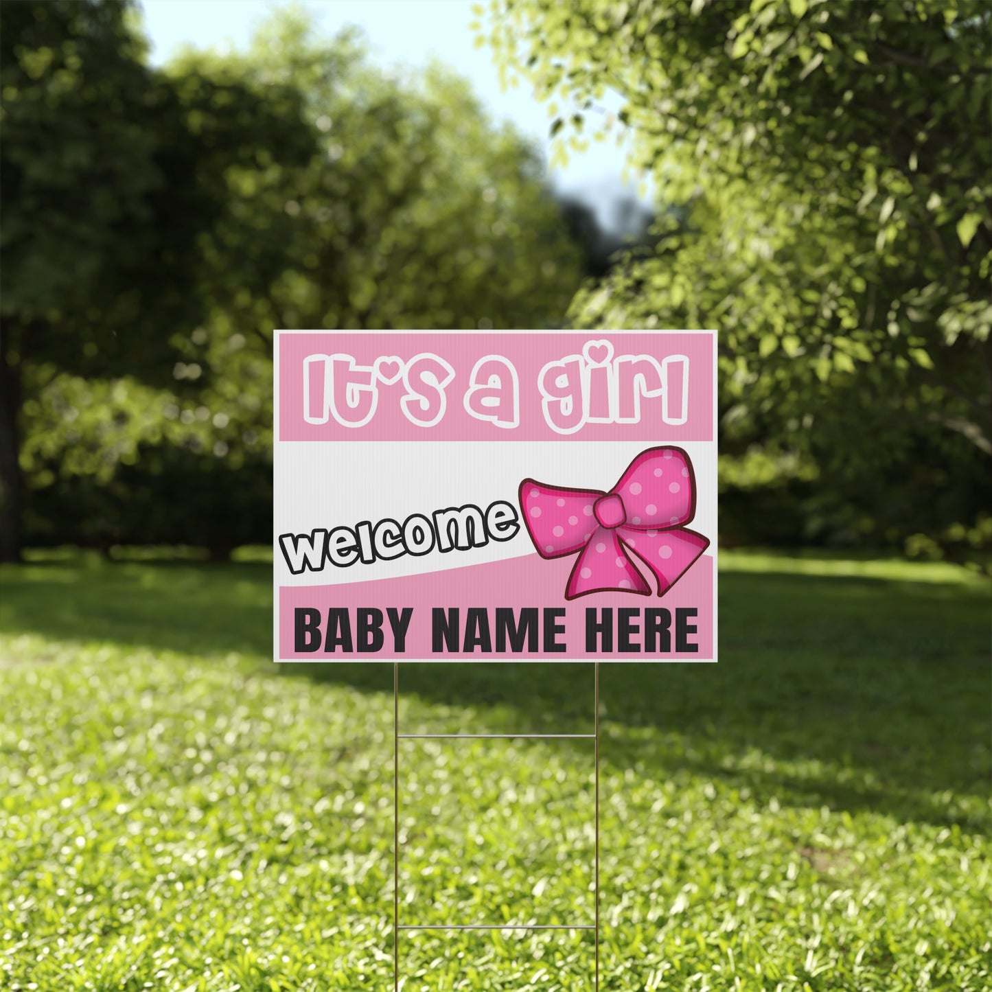Pink baby announcement sign with a bow on grass