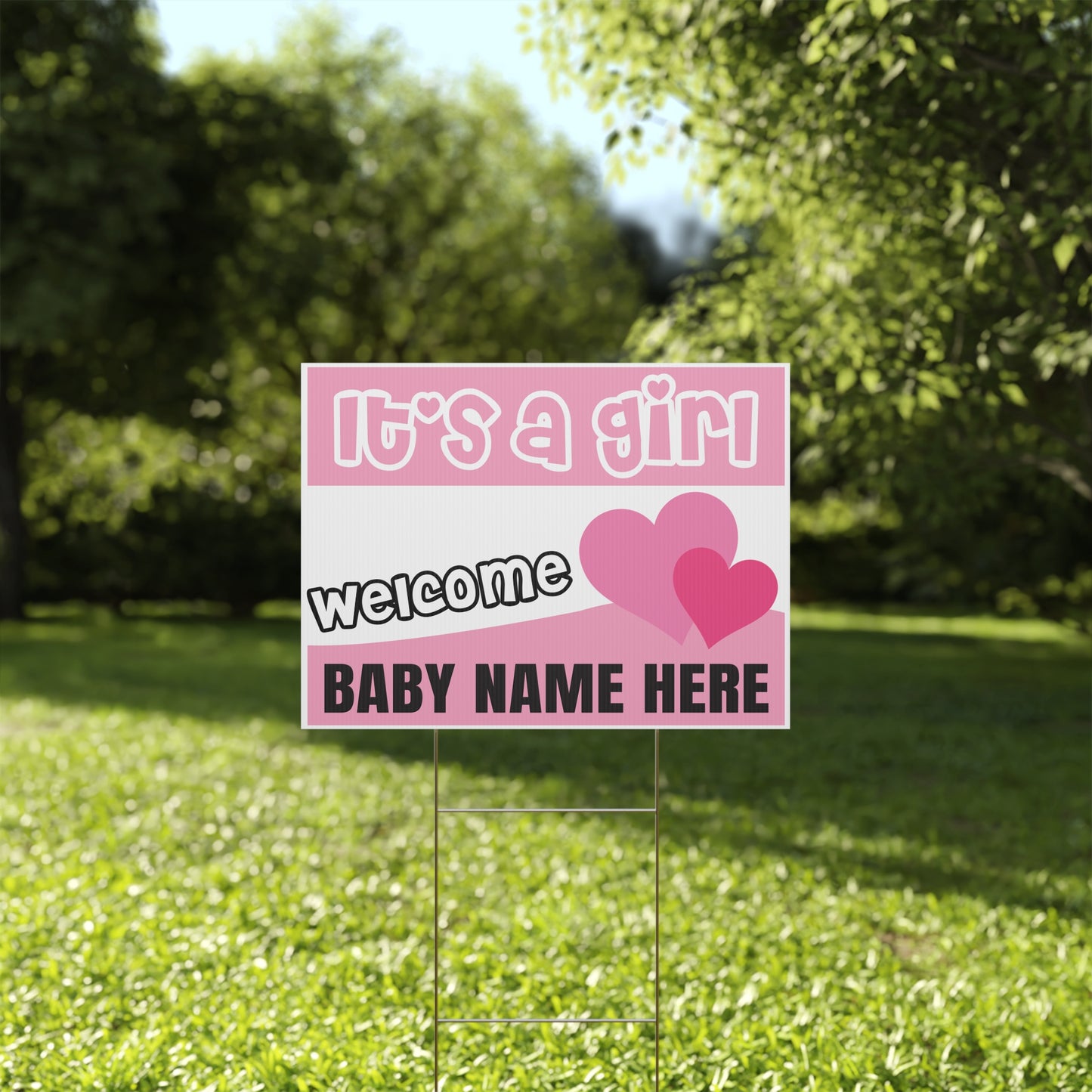 Pink baby announcement sign with hearts on a grassy background