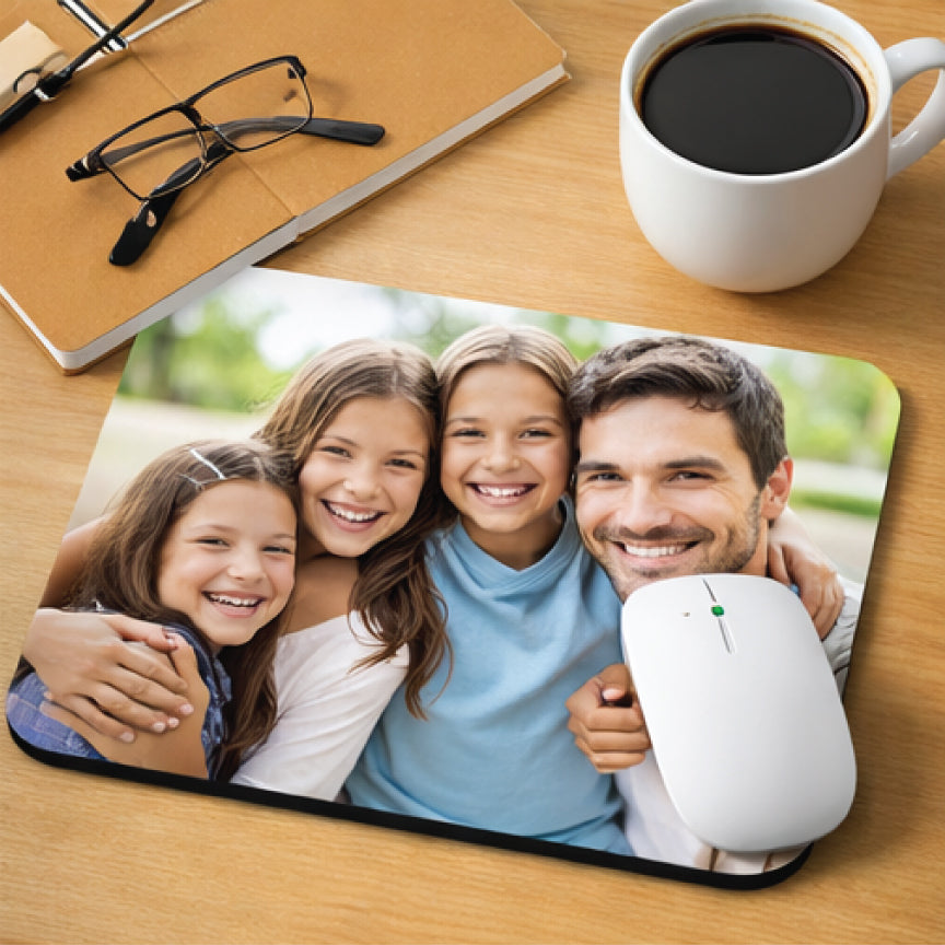 Mouse pad with a family photo on a desk with a cup of coffee and glasses.