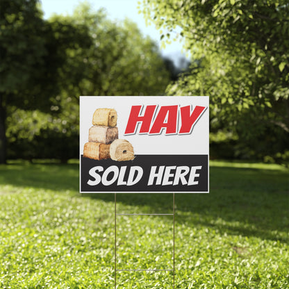 Hay sold here sign on a grassy lawn with trees in the background