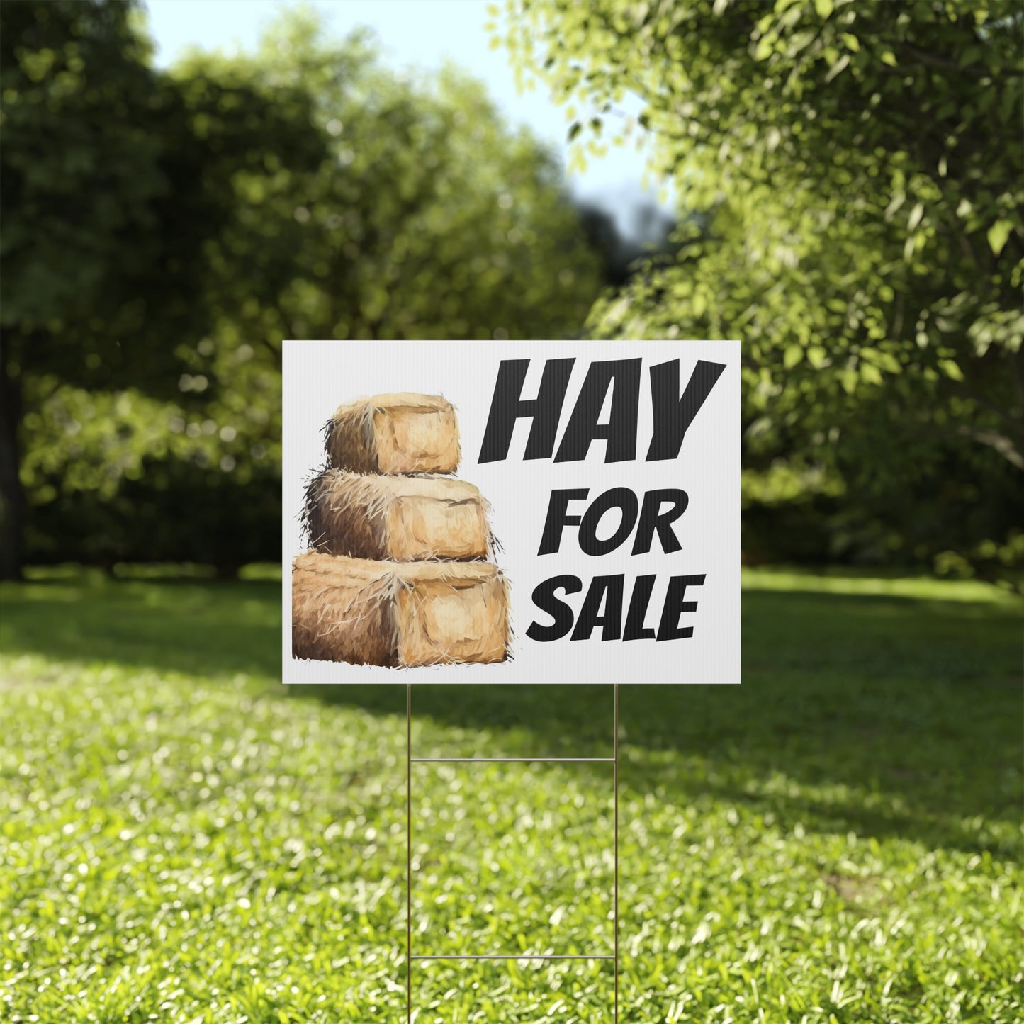 Hay for sale sign on a grassy lawn with trees in the background