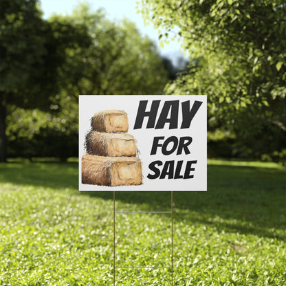 Hay for sale sign on a grassy lawn with trees in the background