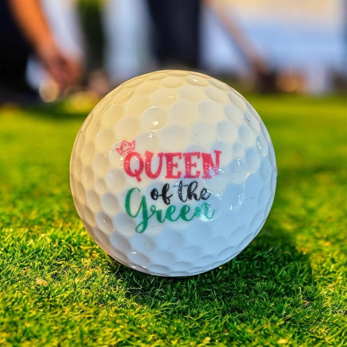 Golf ball with 'Queen of the Green' text on grass